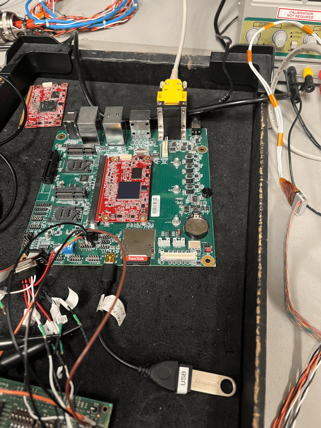 Green PCB carrier board with a red NXP i.MX6 system-on-module installed, showing SIM slots, Ethernet jacks, and a coin-cell battery