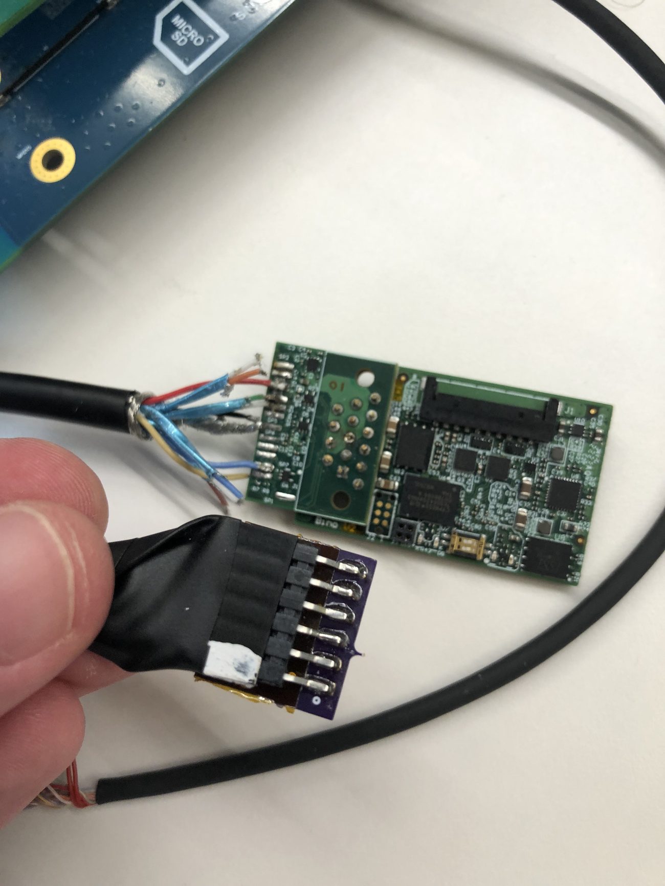Two small green driver PCBs with a soldered wire harness and pin header, on a workbench